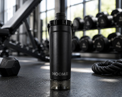 NooMii ProShake 600 in Schwarz im Fitnessstudio neben Hanteln und Battle Ropes